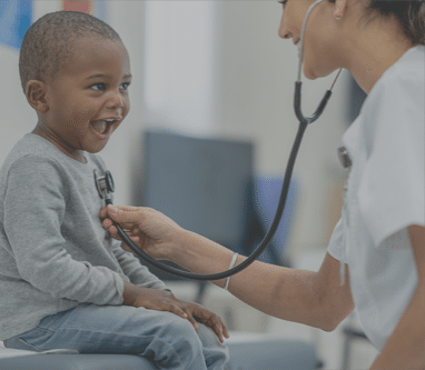 Smiling child being examined by a female doctor with a stethoscope