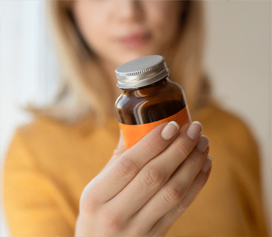 Woman holding a brown medicine bottle with an orange label