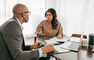 Two professionals in a meeting, reviewing documents at a desk