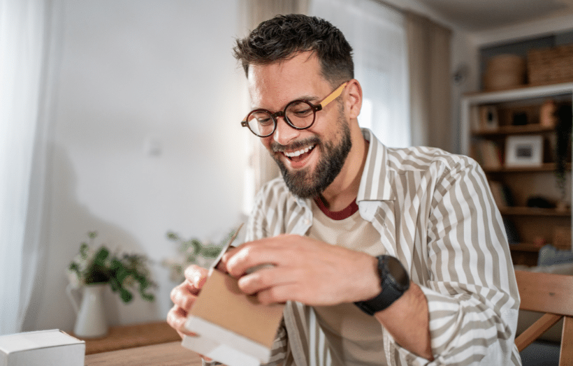 Man smiling as he opens a direct mail package received at home