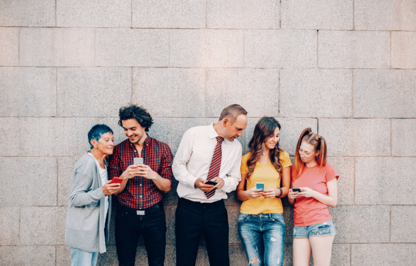 Five people of different generations using smartphones while standing outdoors
