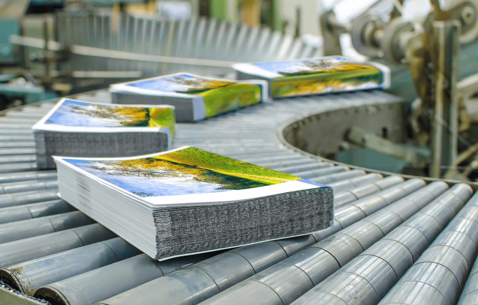 Stack of printed catalogs on production line conveyor for dealer collateral fulfillment