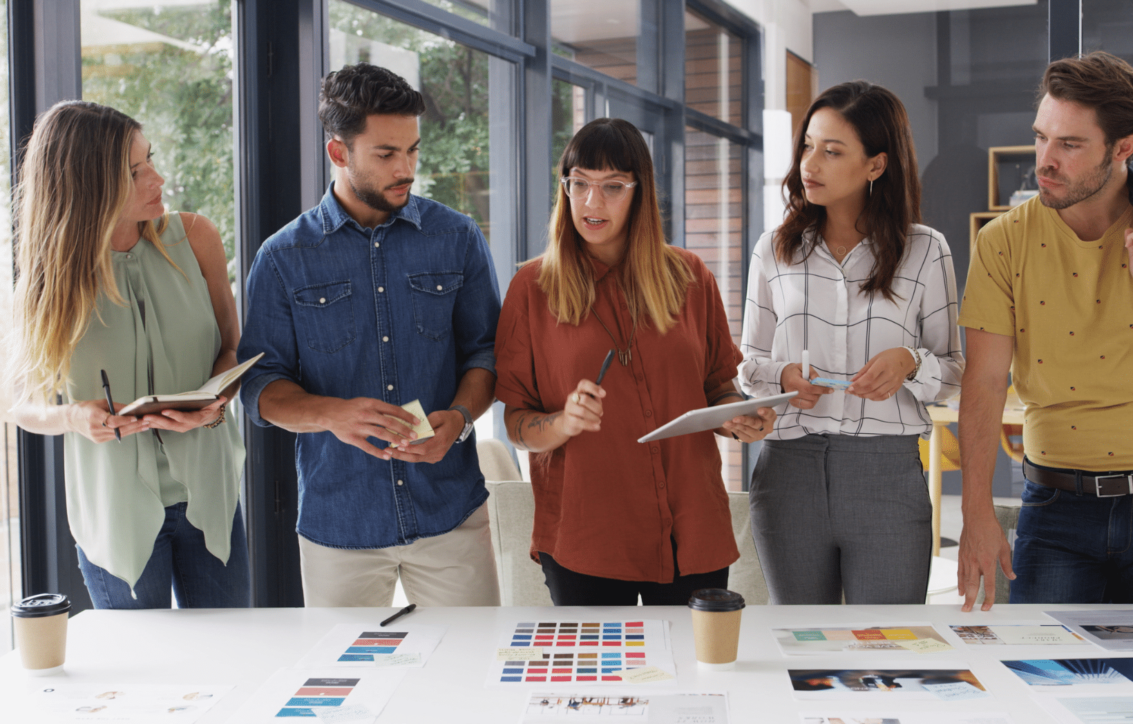Marketing team reviewing print materials, color palettes, and campaign imagery for a direct mail optimization project
