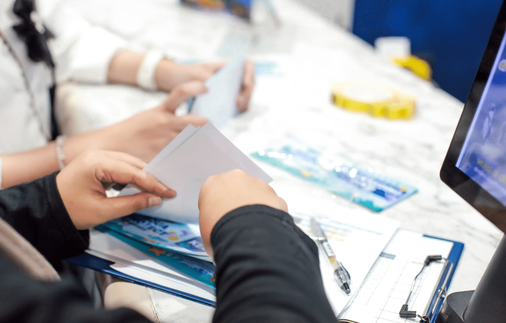 Associates sorting printed materials at a print fulfillment workstation with order paperwork and a laptop